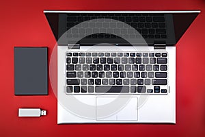 A flash drive, an external hard drive and an open laptop on a red desk