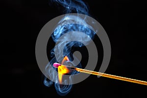 Flashed and burning wooden match on a dark background close-up. Bright fire and smoke from a burning tree