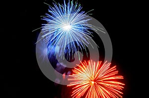 Flashes of blue red green fireworks against the black sky