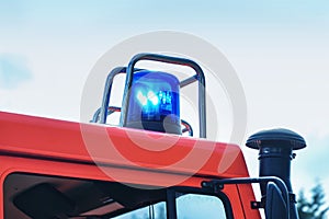 Flashing blue light on a fire truck in duty, part of the vehicle, copy space in the sky, motion blur