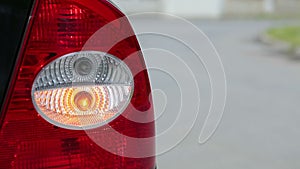Flashing orange blinker light on rear lamp of car, close up view