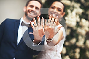 Flashing our symbols of love. Shot of a happy newlywed young couple showing their rings on their wedding day.