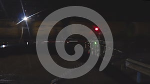 Flashing red traffic light at a railway crossing at night on background of a passing train