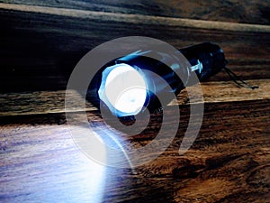 Flashlight light in the dark on wooden background. Torchlight. photo