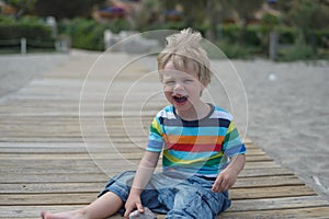 Flashy boy sits on a wooden walkway on the beach