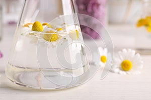 Flask with flowers on table. Extracting essential oil for perfumery and cosmetics