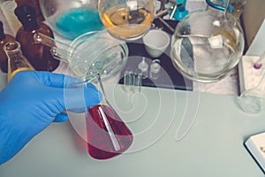 Flask in the hand of a scientist with red liquid in the laboratory