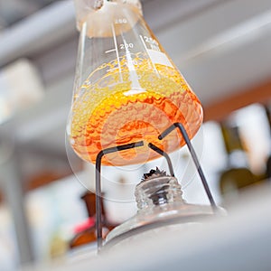 Flask with orange liquid boiling in lab