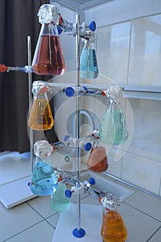 Flasks with colored liquids inside set in the laboratory stand on the worktable, chemical lab