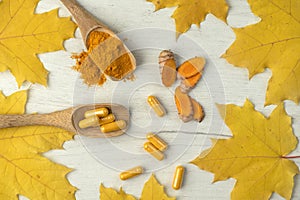 Flat background with turmeric in different shapes Pills and powder in a wooden spoon and root cut into pieces Stacked image