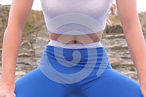 Flat belly girl during diaphragmatic breathing exercises bodyflex on the rock background. Belly close-up view.