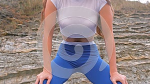 Flat belly girl during diaphragmatic breathing exercises bodyflex on the rock background. Belly close-up view.