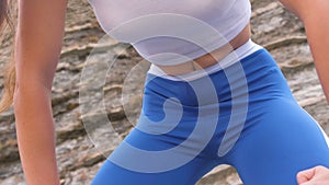 Flat belly girl during diaphragmatic breathing exercises bodyflex on the rock background. Belly close-up view.