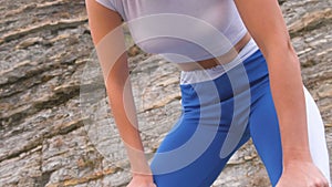 Flat belly girl during diaphragmatic breathing exercises bodyflex on the rock background. Belly close-up view.