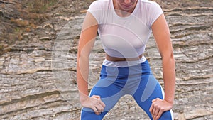 Flat belly girl during diaphragmatic breathing exercises bodyflex on the rock background. Belly close-up view.