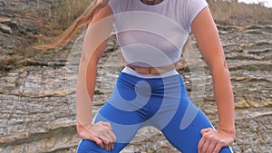 Flat belly girl during diaphragmatic breathing exercises bodyflex on the rock background. Belly close-up view.