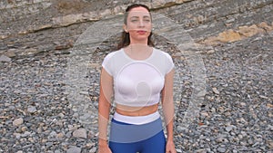 Flat belly girl during diaphragmatic breathing exercises bodyflex on the rock background. Face and body close-up view.