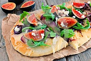 Flat bread pizza with figs, arugula, goat cheese, over wood