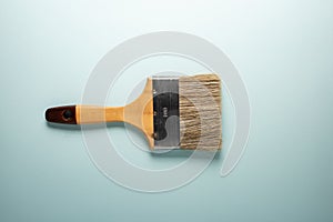 Flat brush with wooden handle on a turquoise background