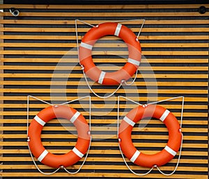 Flat closeup of three red lifebuoys wall on white