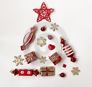 Flat composition with a Christmas tree made of different festive items, snowflakes, gifts, sweets on a white background