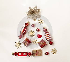 Flat composition with a Christmas tree made of different festive items, snowflakes, gifts, sweets on a white background