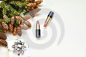 Flat composition with cosmetic products and christmas decor on white backgroun. Gift box and lipsticks, fir branch. Stylish Christ