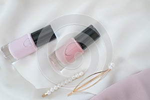 A flat composition of nail polish and golden female hairpins decorated with pearls. Modern and fashion spring or summer