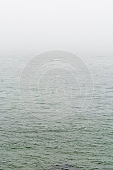 Flat grey sea with wavelets in the fog