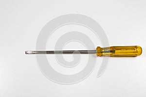A flat-head screwdriver with handle yellow and lomg end. on a mottled white surface photo