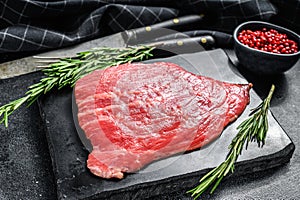 Flat iron steak. Raw Marble beef meat black Angus. Black background. Top view