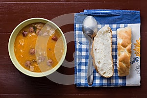 Flat lay above cooked beans with sausages and bread on the kitch