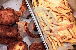 Flat lay above table with fried chicken wings and french fries in the box. Served unhealthy meal. Fast food meal in the paper box.