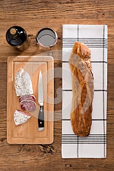 Flat lay above view of dry sausage delicatessen sliced meat with wine and traditional bread on wooden board