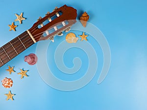 Flat lay of acoustic guitar with sea shells and starfishes on blue background, copy space. Summer beach acoustic music background