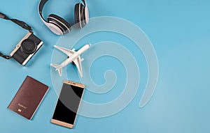 Flat lay of airplane model, passport, camera, headphones and mobile phone on blue background. Traveling accessories concept