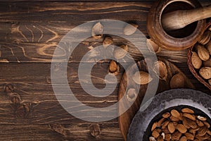 Flat lay of almonds in black plate with other accessories on brown wooden background top view