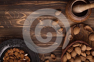 Flat lay of almonds in black plate with other accessories on brown wooden background top view 2