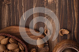 Flat lay of almonds in the wicker plates with other accessories on brown wooden background top view 12