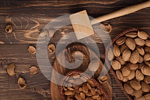 Flat lay of almonds in the wicker plates with other accessories on brown wooden background top view 8