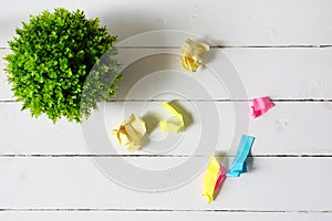 Flat lay of artificial green plant and crumple colorful papers