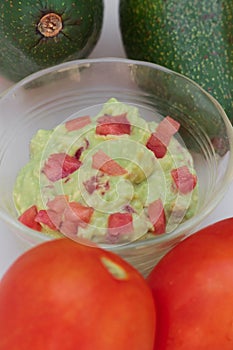 Flat lay of avocadoes, tomatoes, and guacamole sauce in a bowl