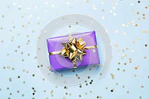 Flat lay background for celebration Christmas and New Year. Gift boxes are purple with gold ribbons bows and confetti stars on a