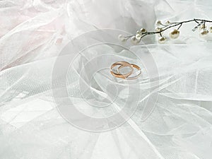 Flat lay background with a pair of gold rings and pearl necklace for wedding or engagement decorated with white lace of a veil of