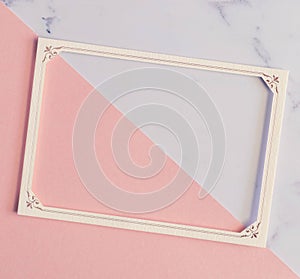 Flat lay of beige paper frame with white flower as decoration on marble background