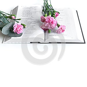 Flat lay: Bible and pink, red, rose flower bouquet. On white background