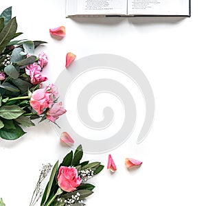 Flat lay: Bible and pink, red, rose flower bouquet. On white background