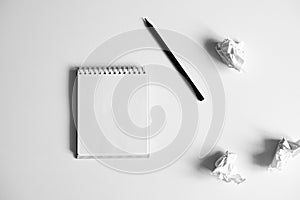 Flat lay of blank white notepad, pencil and crumpled paper on white background