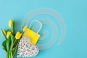 Flat lay blue background with flowers and paper bags.