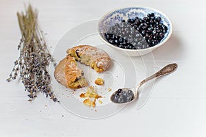 A flat lay of a blueberry muffin , blueberry bowl and flowers of lavender on a white background